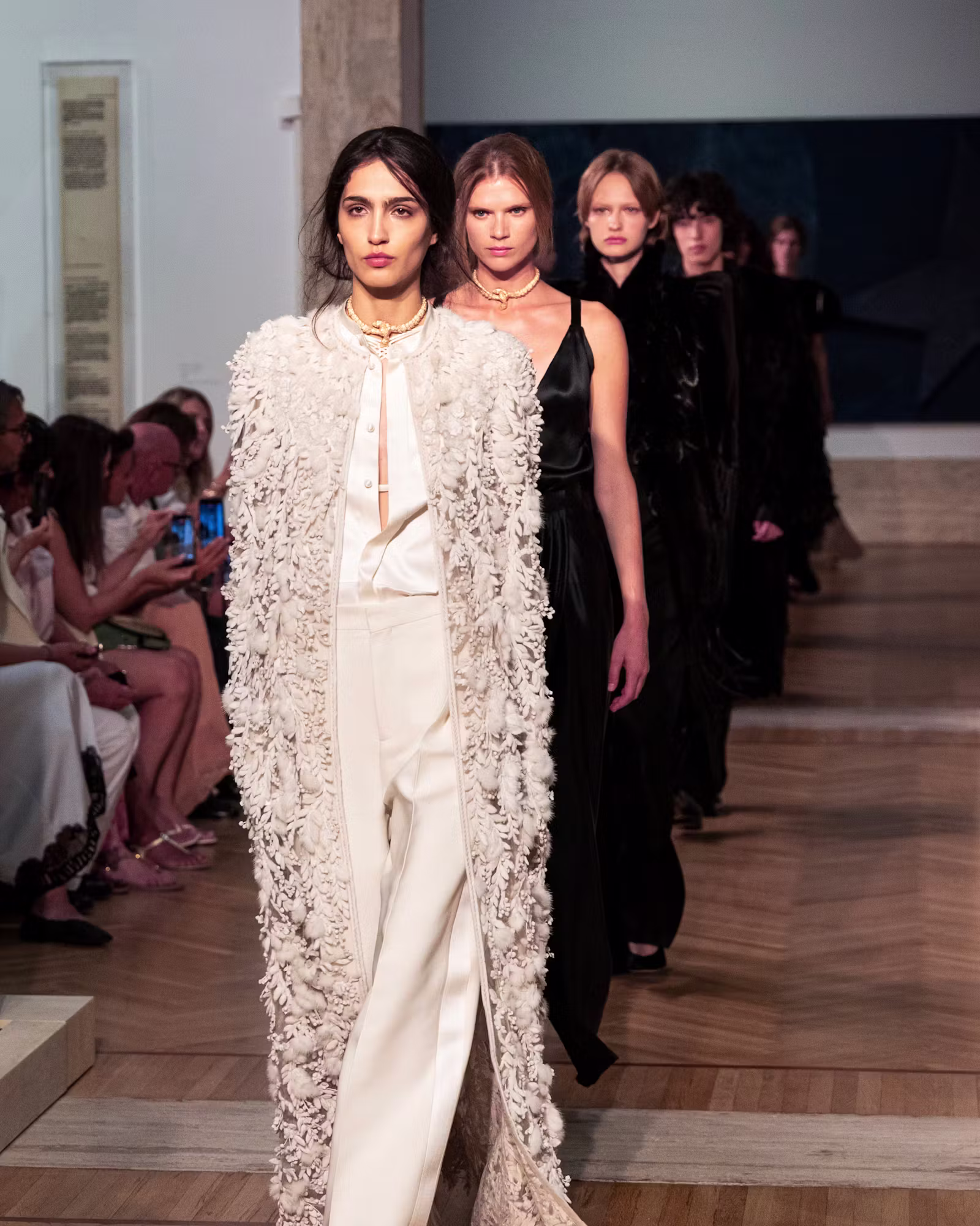 look bridal da Fendi alta-costura inverno 2026 com calças de alfaiataria, blusa de seda e casaco longo bordado com aplicações florais tridimensionais