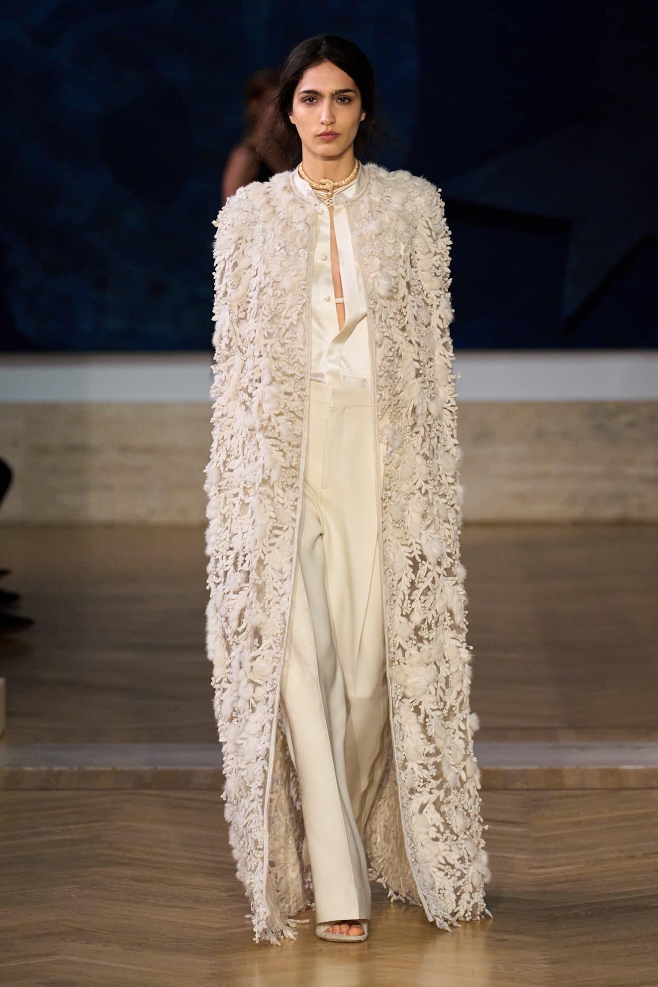 look bridal da Fendi alta-costura inverno 2026 com calças de alfaiataria, blusa de seda e casaco longo bordado com aplicações florais tridimensionais